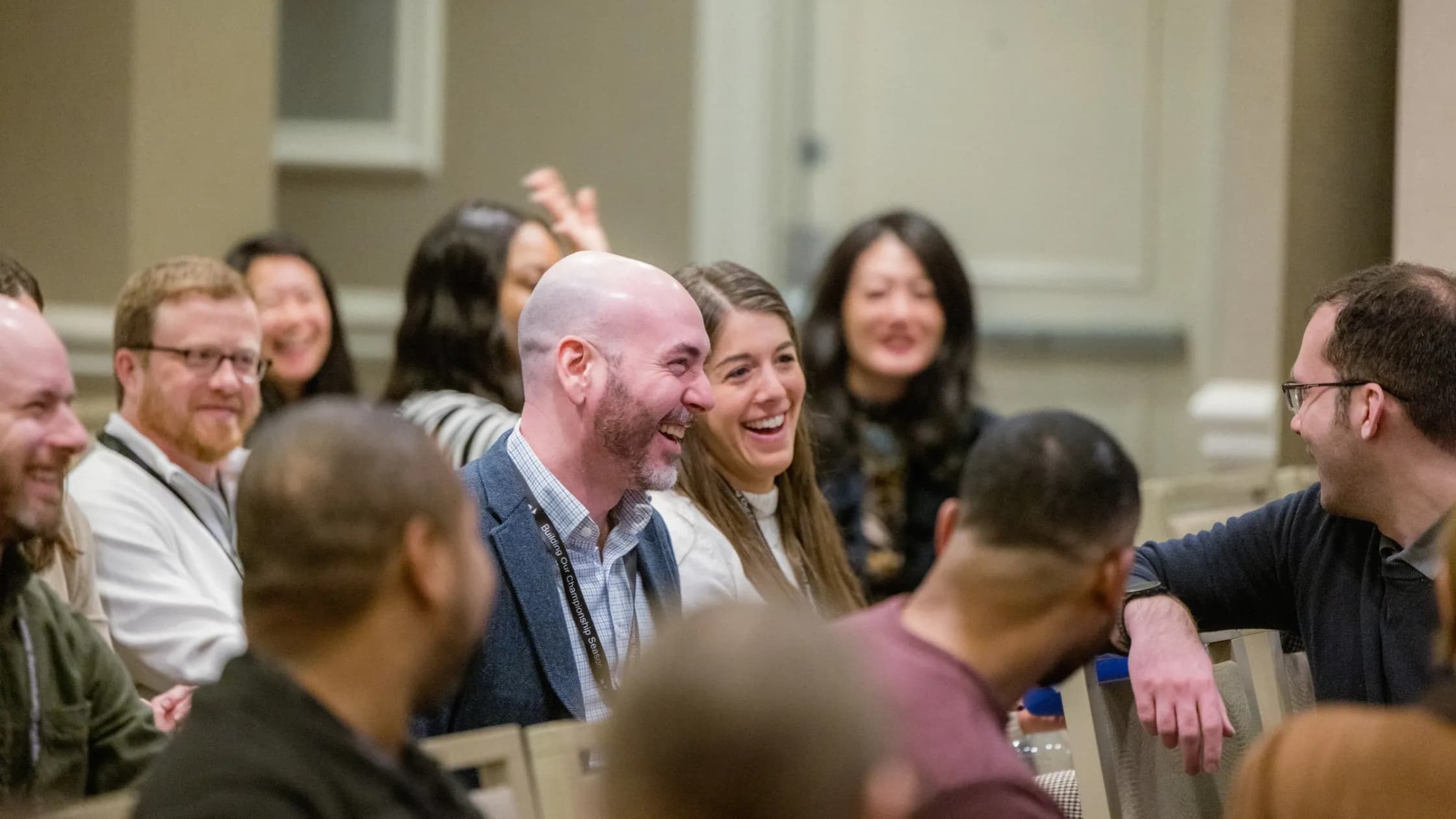 Brian Schwartz and Starr Ruiz laughing during Acquis annual meeting surrounded by other team members